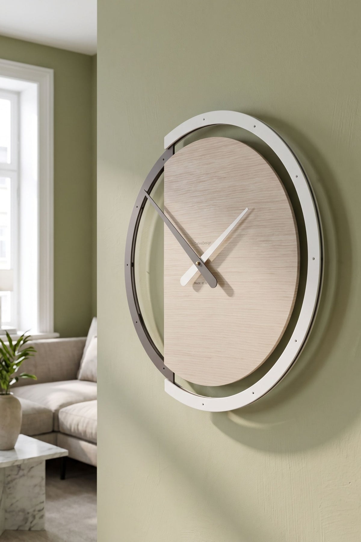 CalleaDesign Zaki wall clock in Pickled Oak finish on a soft green wall in a contemporary living room