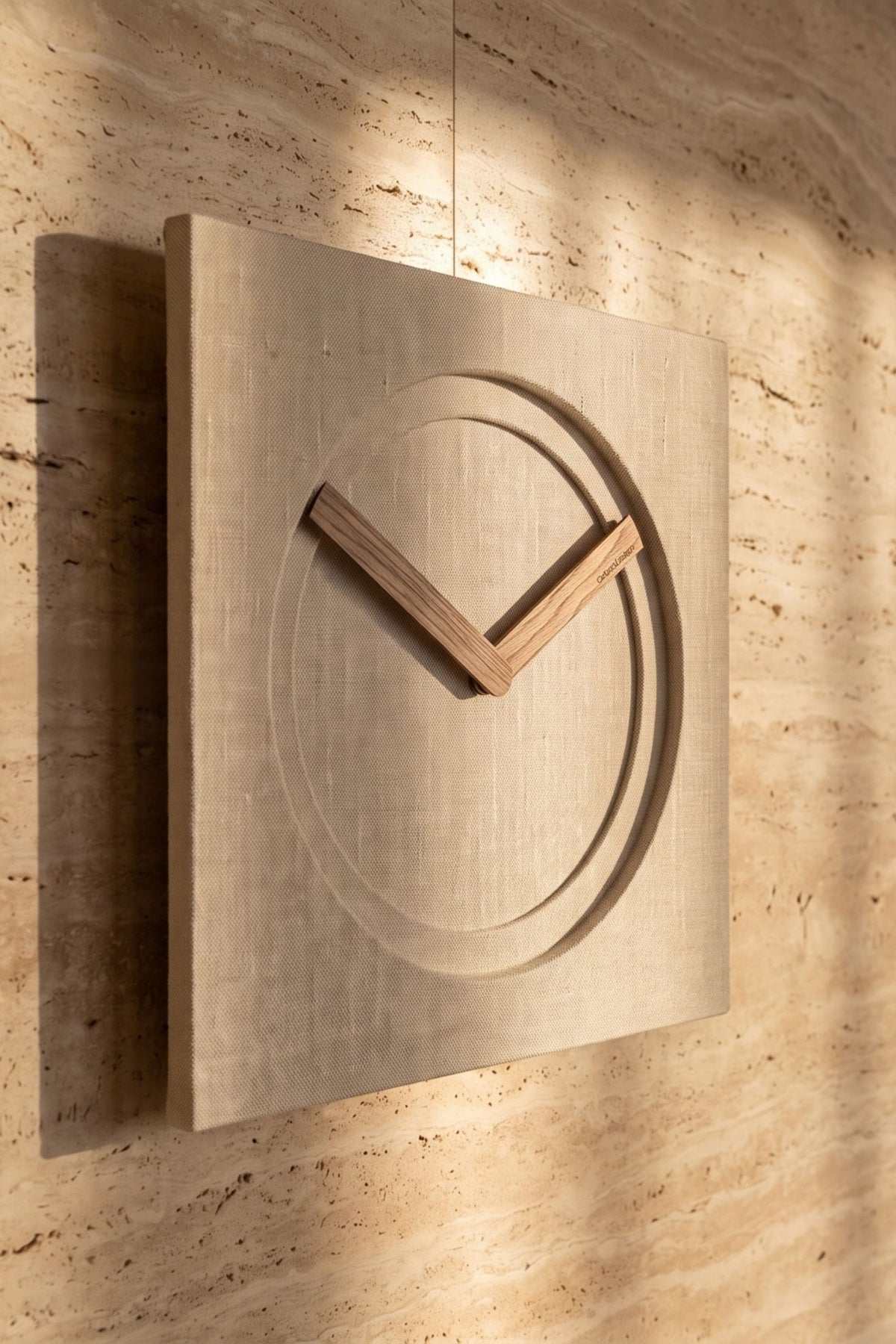 KAM 1 Limited Edition wall clock with a natural linen finish and Canaletto walnut hands on a warm stone wall