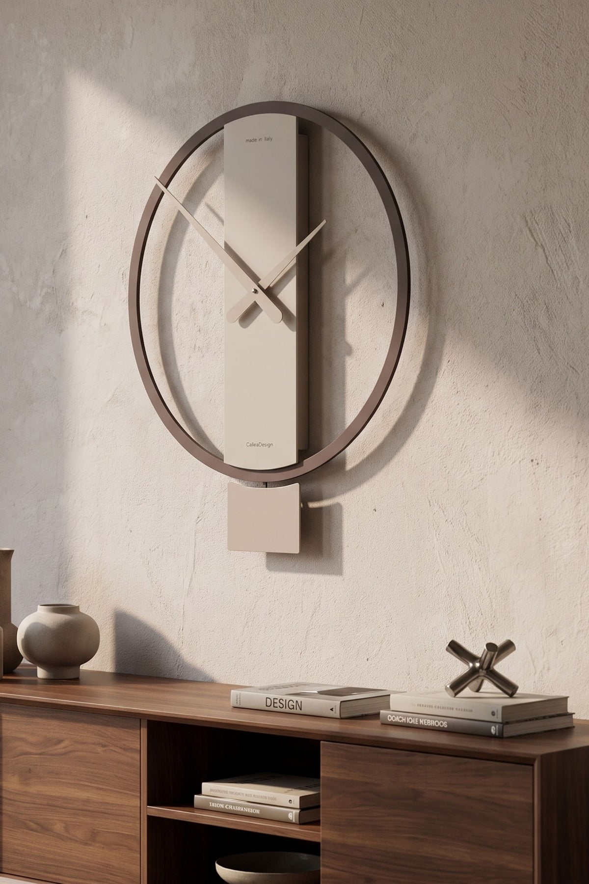 CalleaDesign Kurt pendulum clock in a neutral finish above a walnut sideboard in a contemporary interior