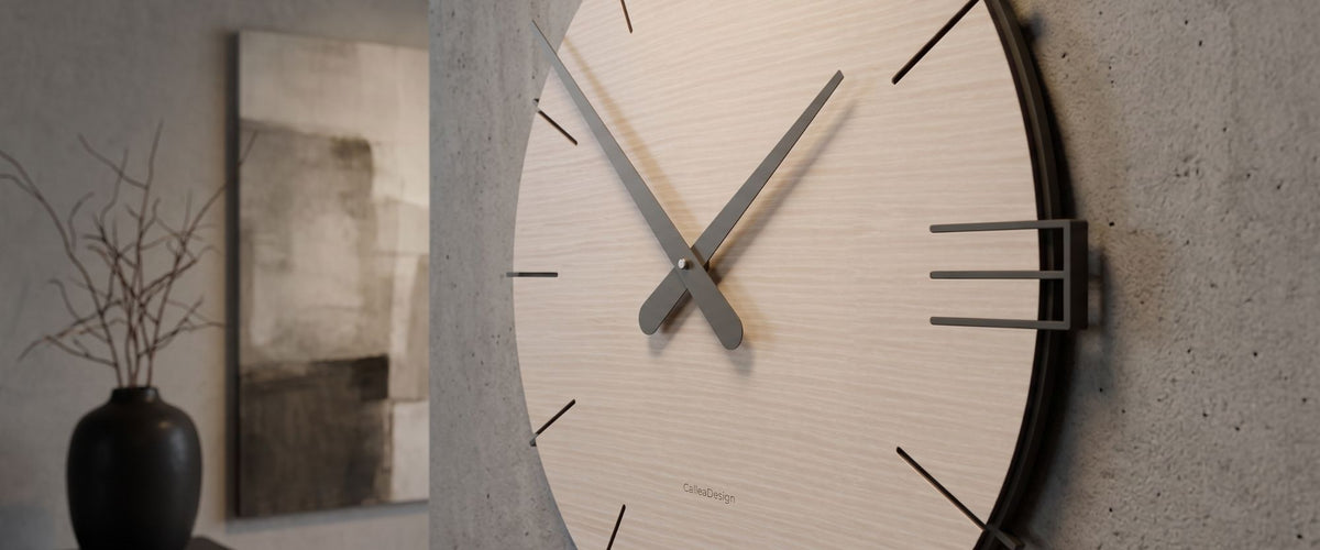 Gros plan d’une horloge murale CalleaDesign au cadran en bois clair et aux aiguilles foncées dans un intérieur contemporain