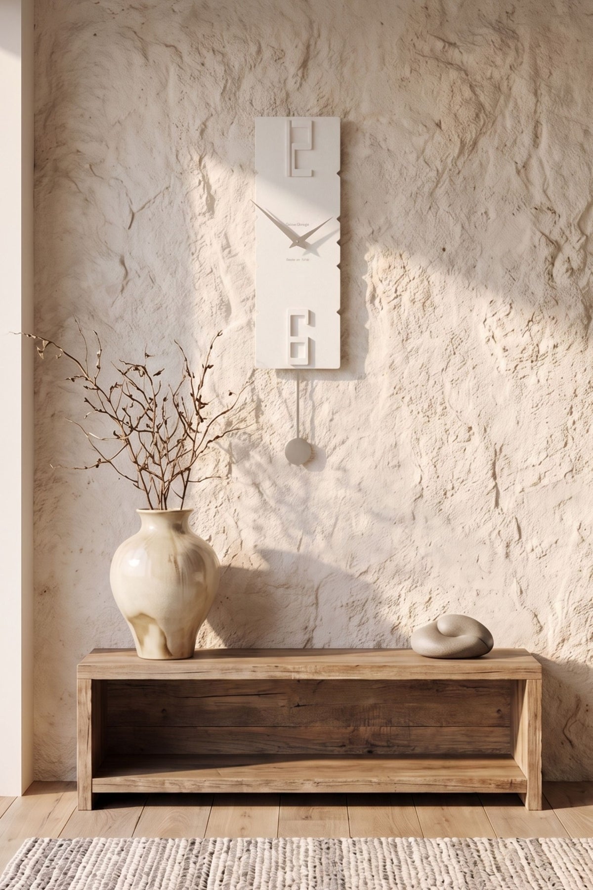 CalleaDesign Rock pendulum clock in white finish on a textured wall in a warm natural interior
